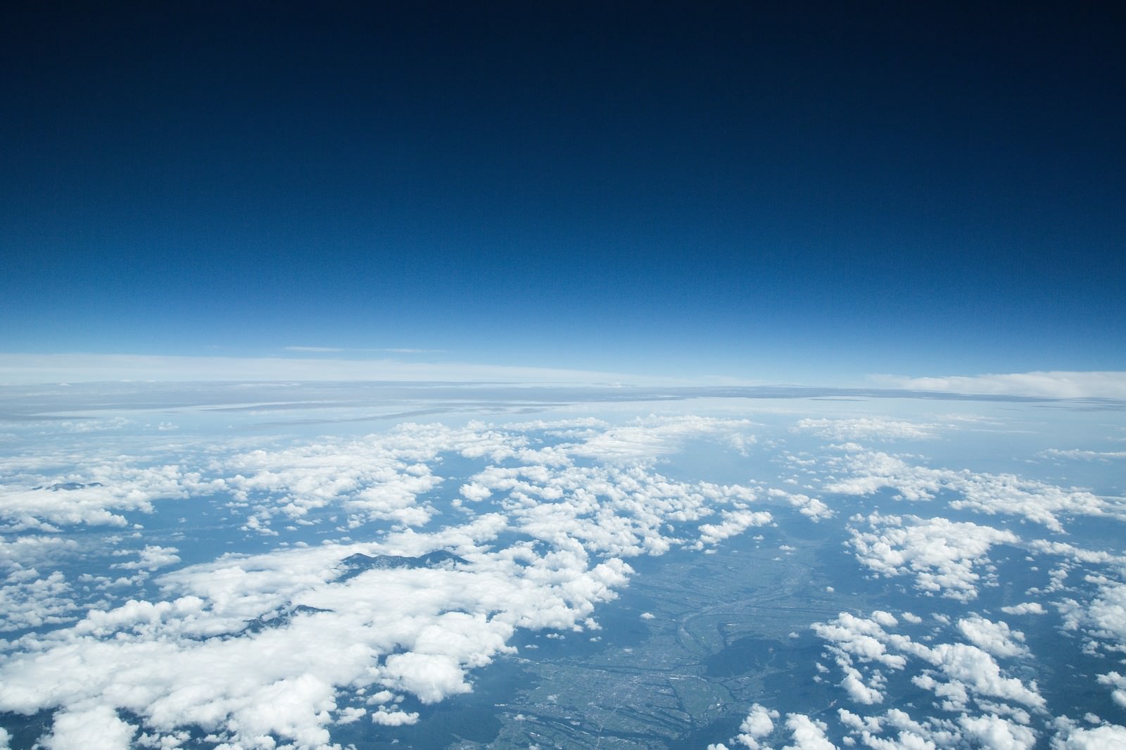 雲海の上に広がる深い青空と地球の曲線が見える上空の景色