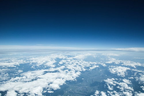 雲海を抜けた濃い青空と地球の曲線が見える高高度からの眺望