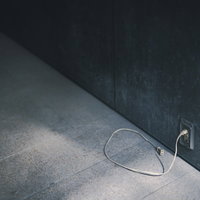 古びた白い電源コンセントと黒い延長ケーブルの写真