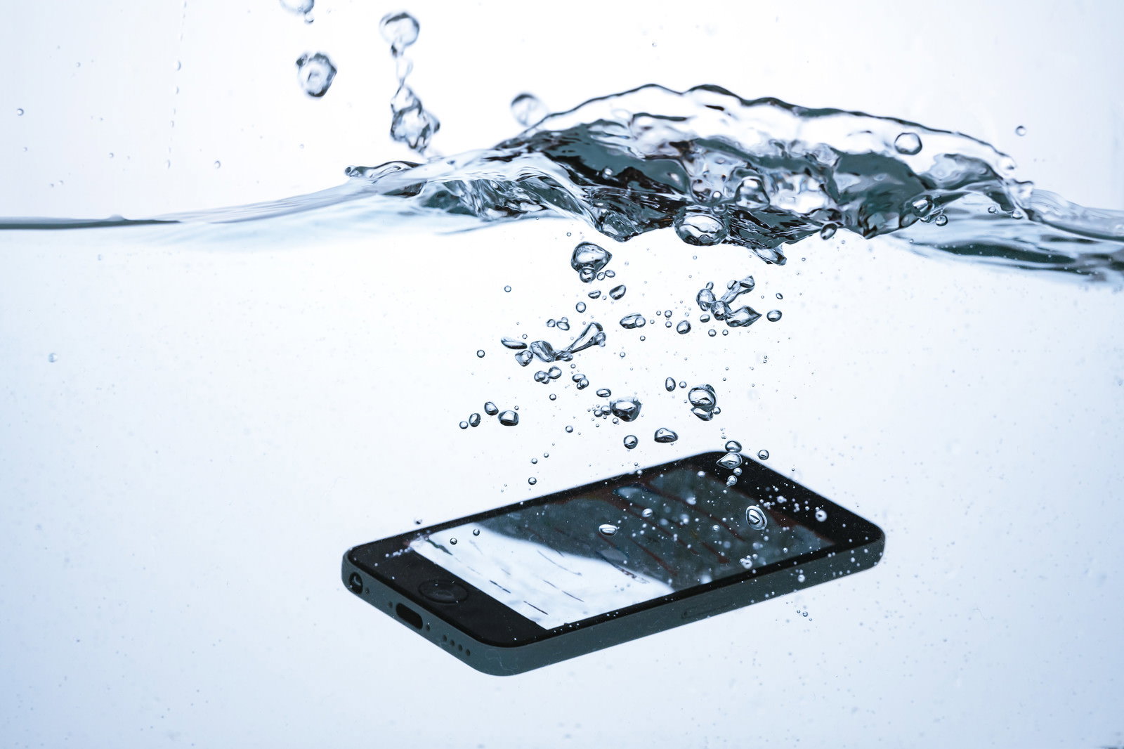 水中に落下する黒いスマートフォンと水しぶき