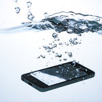 スマートフォンが水に落ちて水没する瞬間の水しぶきの写真
