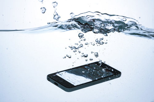 スマートフォンが水に落ちて水没する瞬間の水しぶき