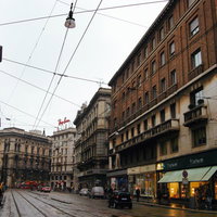 ミラノの街角に立ち並ぶレンガ造りの建物と石畳の街並みの写真