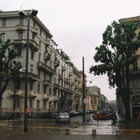 ミラノの街角に駐車する車と石造りの建物が立ち並ぶ街並みの写真
