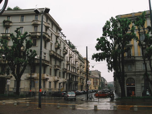 ミラノの街角に駐車する車と石造りの建物が立ち並ぶ街並み