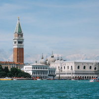 ヴェネツィアの水路越しにみえる大鐘楼とサンマルコ寺院の屋根（イタリア）の写真
