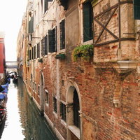 ヴェネツィアの水路に浮かぶゴンドラとレンガ造りの建物（イタリア）の写真