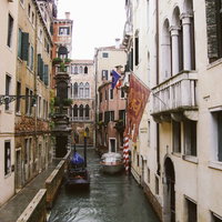 ヴェネツィアの水路に浮かぶ小船と旗が立つ歴史的建物の写真
