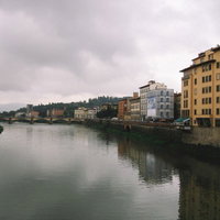 イタリア・フィレンツェを流れる川と遠くに見える橋の写真