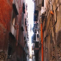 イタリアの古いアパートに挟まれた路地裏の石畳の道の写真