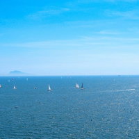 ナポリの青い海と空に浮かぶ白いヨット（イタリア）の写真