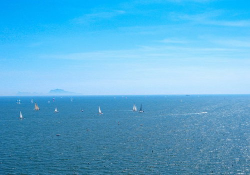 ナポリの青い海と空に浮かぶ白いヨット（イタリア）