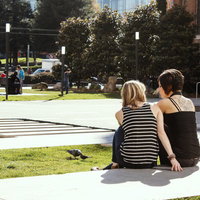 芝生の広場に座る二人の後ろ姿と海外の大学の写真