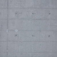 丸い穴やくぼみと縦横の継ぎ目が見えるコンクリート壁のテクスチャーの写真