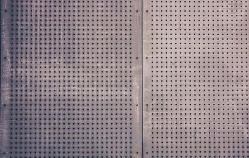 丸い穴が規則的に開いたボルト留めの金属パネルのテクスチャー
