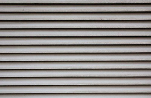 影が落ちた白い横板が並ぶ古いシャッターのテクスチャー