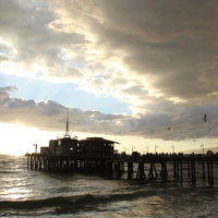 夕暮れの海に建つ木製桟橋と波の写真