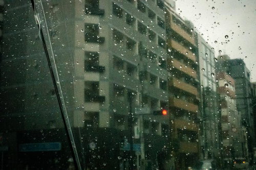 雨粒越しに見える街並みと赤信号