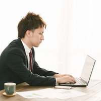 会議の資料をまとめるスーツ姿の会社員男性の写真