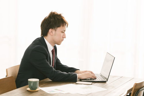 会議の資料をまとめるスーツ姿の会社員男性