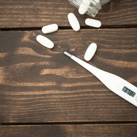 高熱が出たので薬の錠剤を飲む医療対応の写真