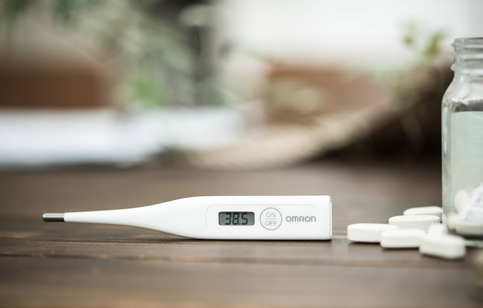 38度5分を示す体温計と風邪薬の錠剤