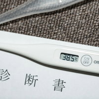 連休中に高熱が出て病院で受け取った診断書と体温計の写真