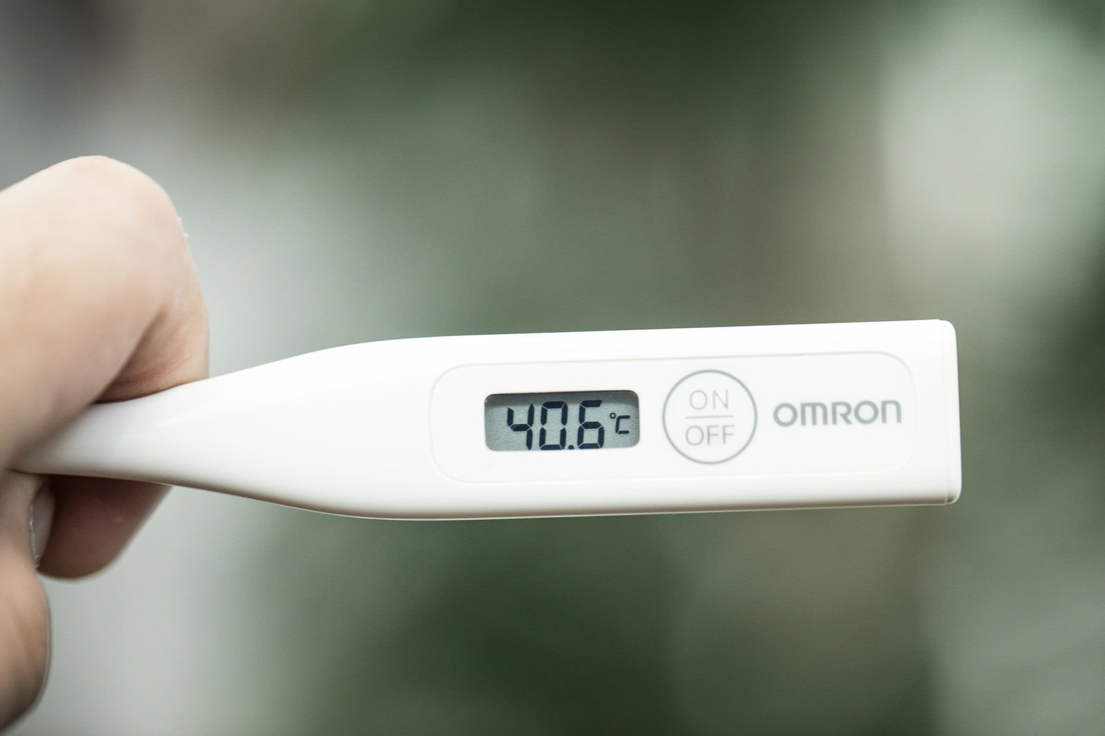 40.6℃を表示するデジタル体温計を手で持つ