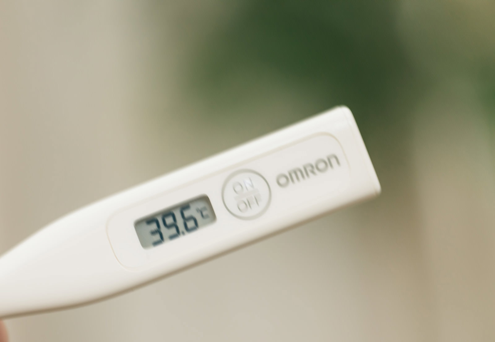40.6℃を表示するデジタル体温計を手で持つ