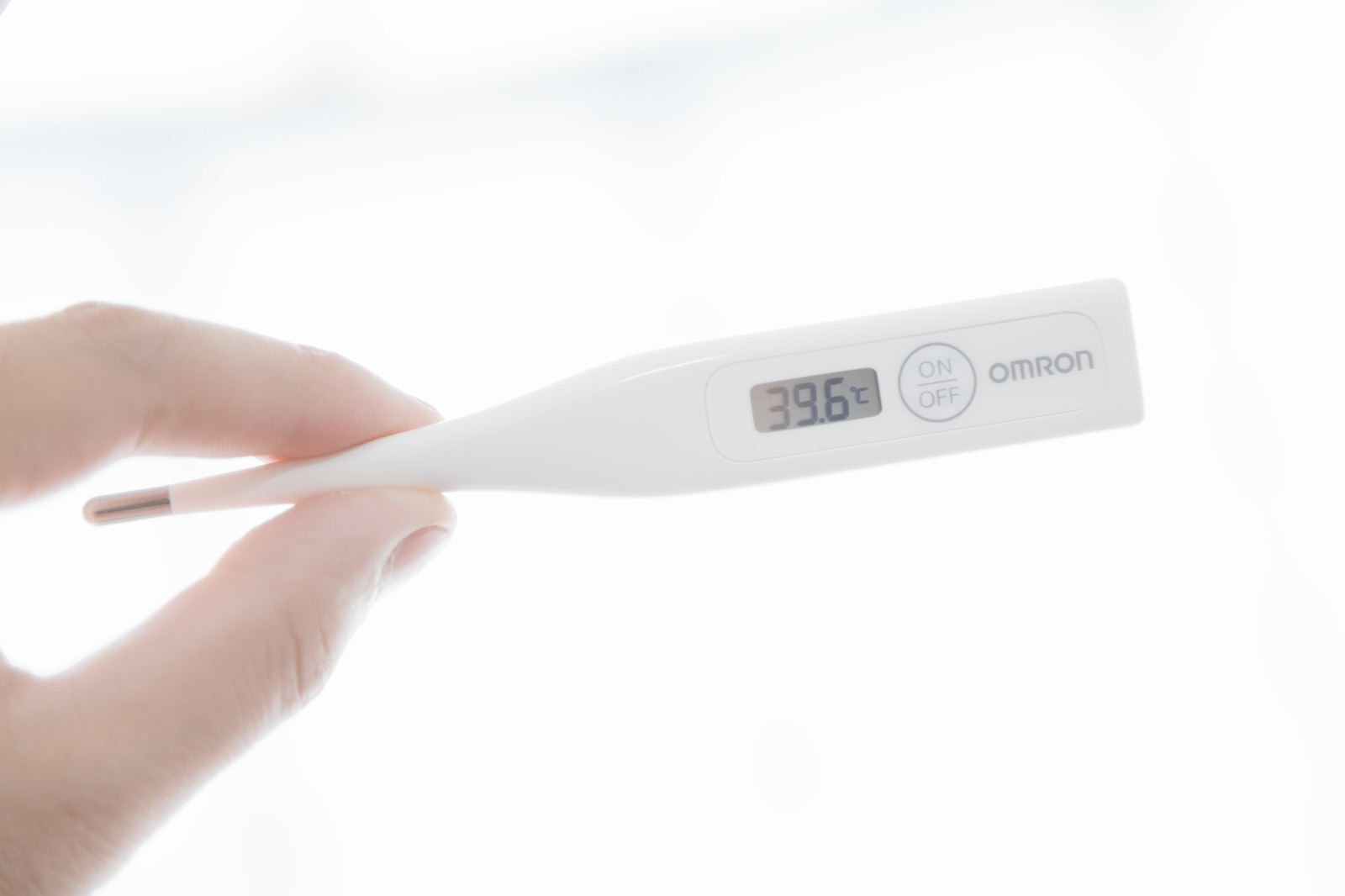 39.6℃を示すオムロンのデジタル体温計を持つ手の写真