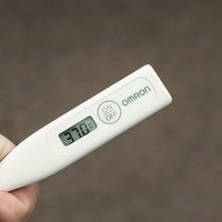 平熱が低いので37℃はツライ、白い電子体温計を手に持つの写真