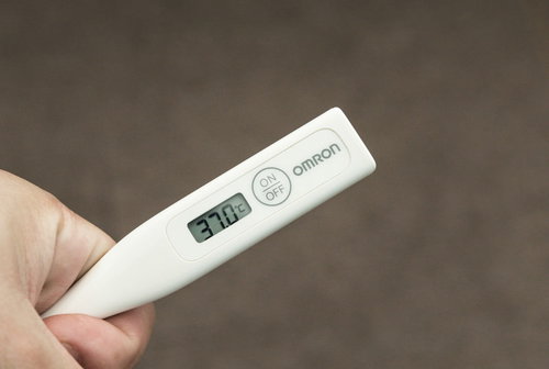 平熱が低いので37℃はツライ、白い電子体温計を手に持つ