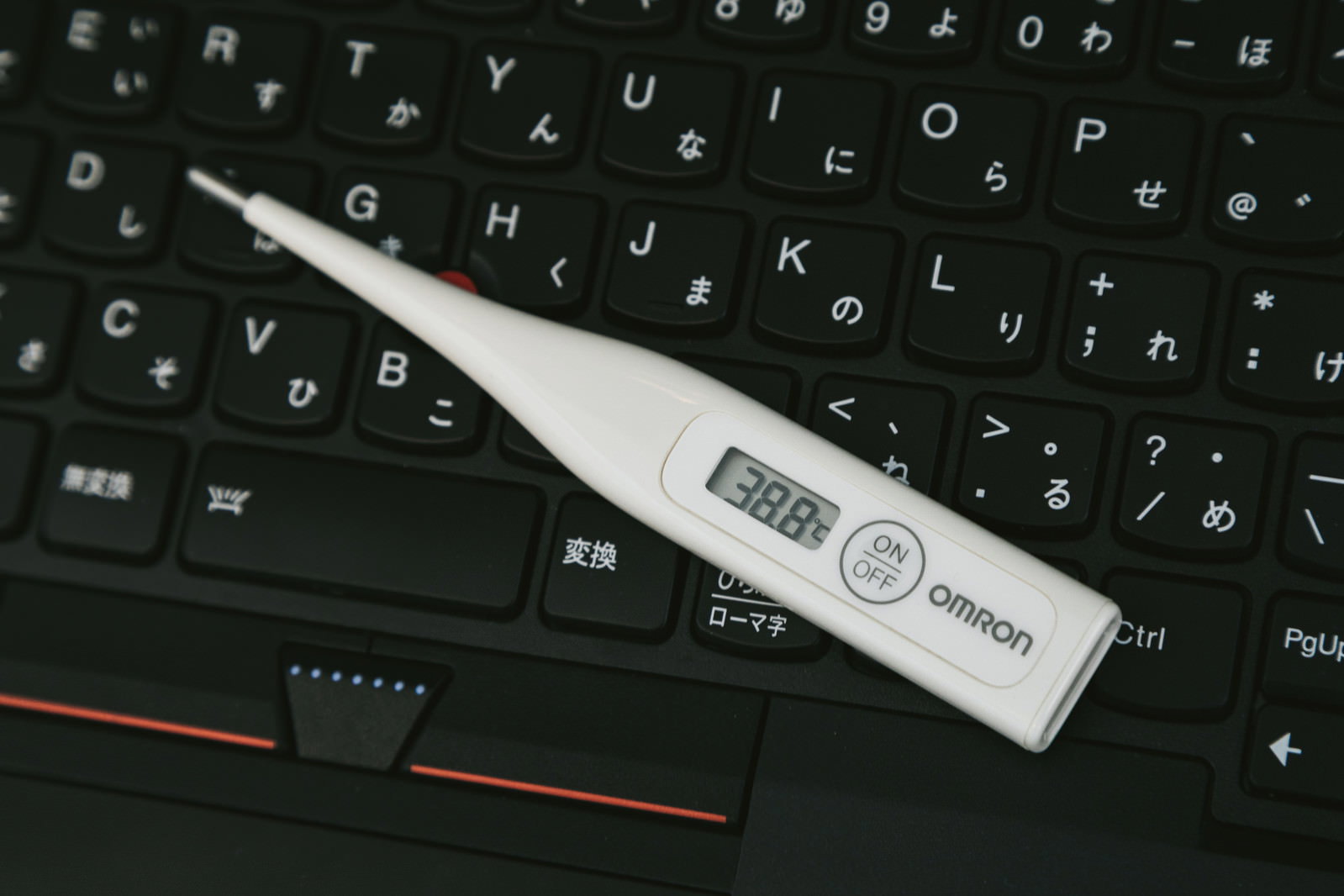 キーボードの上に置かれた38.8℃を示す体温計