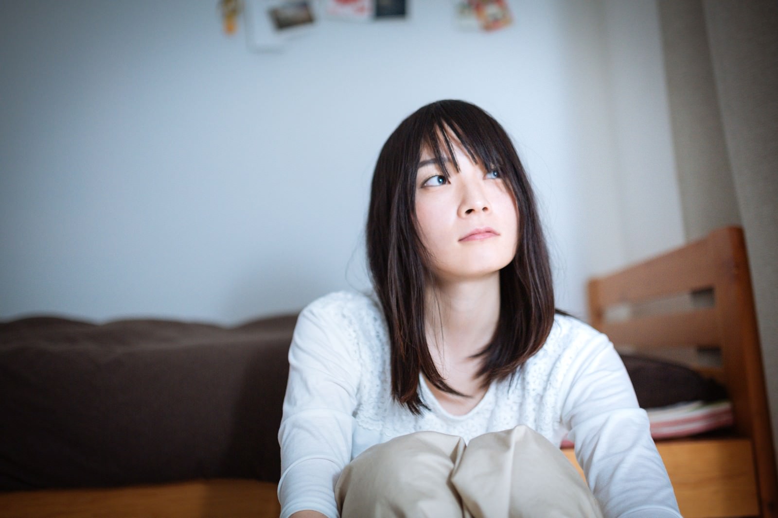 ソファーに座って上を見つめる女性［モデル：たけべともこ］