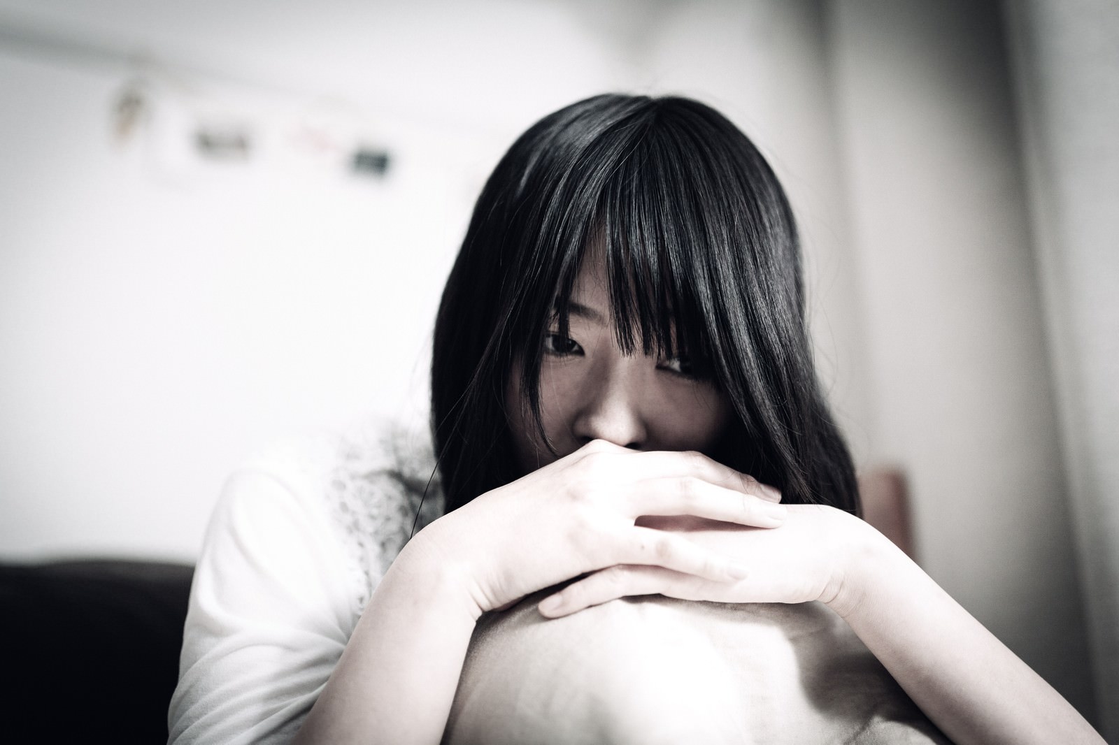 黒髪で俯きながら両手を膝に置く女性［モデル：たけべともこ］