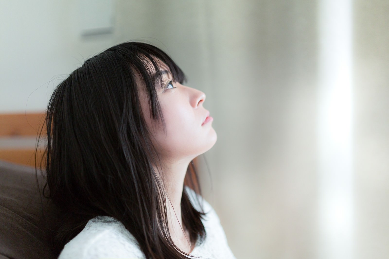 椅子に座り上を見つめる失恋女子、朝日が顔に当たっている［モデル：たけべともこ］