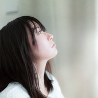 カーテンの隙間から差し込む朝日で目覚める失恋女子の写真