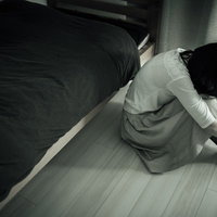 ワンルームで体育座りする憂鬱な朝の失恋女子の写真