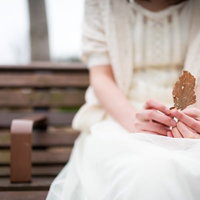 心情と枯れ葉を重ねる、公園のベンチに座る女性の写真