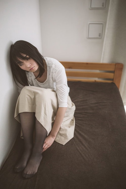 ベッドの上で膝を抱えて下を向く失恋女子の心理描写
