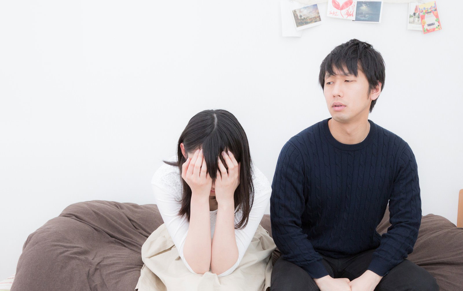 ソファで泣く彼女と沈黙する彼氏［モデル：たけべともこ 大川竜弥］