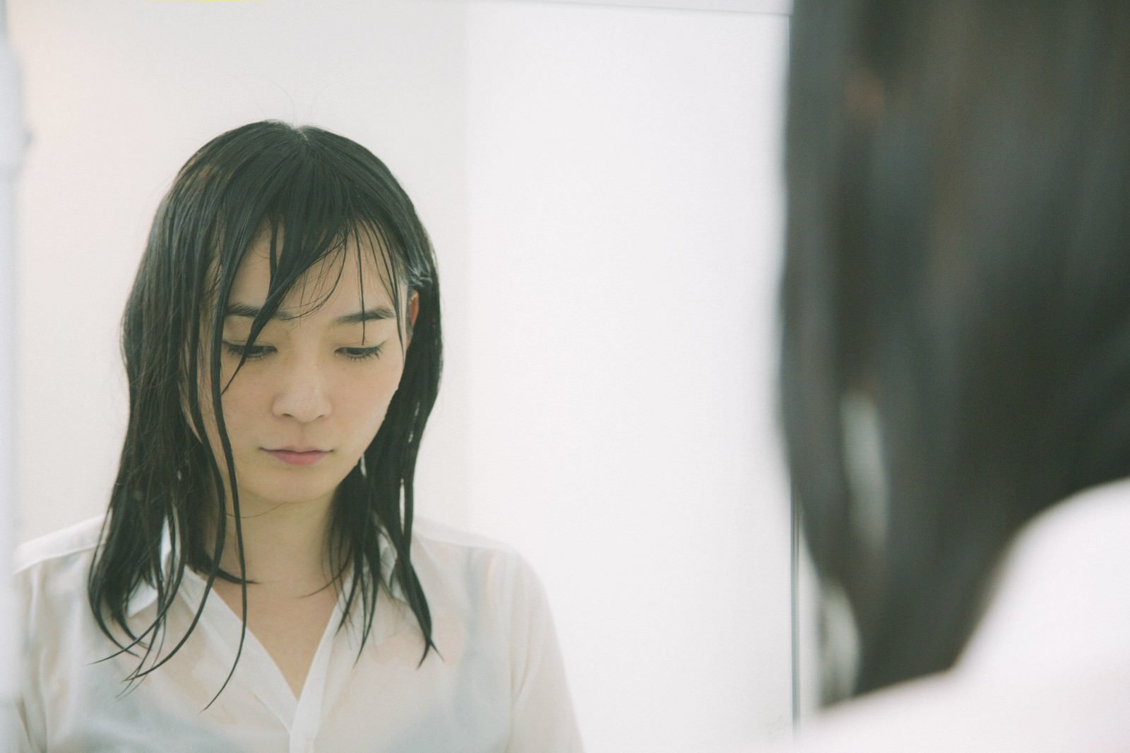 土砂降りの中で傘をささずに歩く濡れた髪の女性の横顔［モデル：たけべともこ］