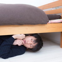 ベッドの下に隠れて妻をつけまわすストーカー男性の写真