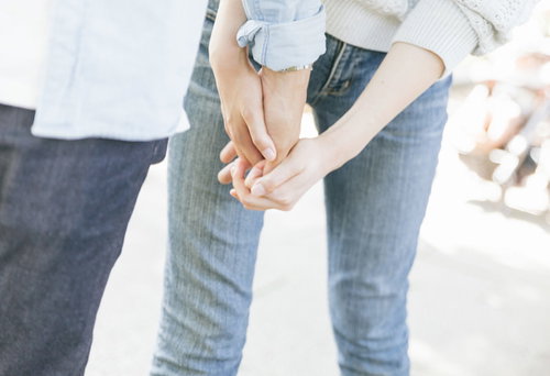 誰かと手をつなぐ若い女性（屋外）