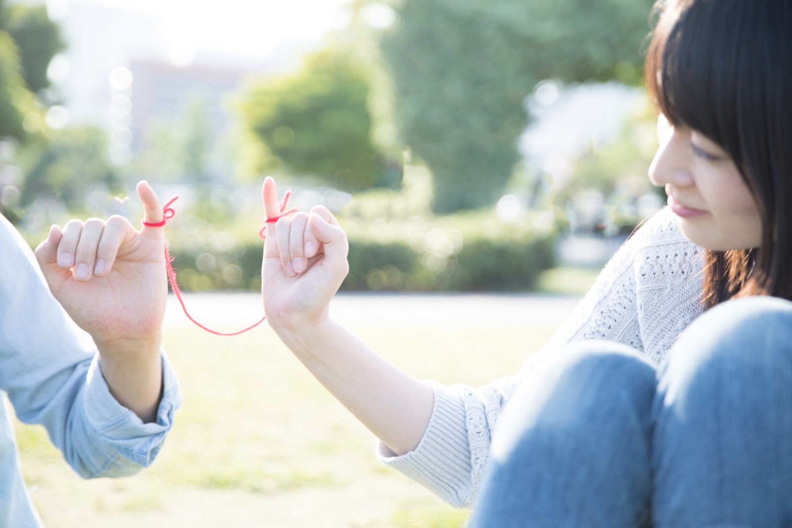 カップルが指と指を繋いで赤い糸を表現している様子［モデル：たけべともこ］