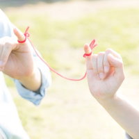 赤い糸で結ばれた恋人同士の手が温かい光に包まれるシーンの写真