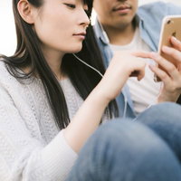 彼氏とお気に入りの動画をイヤホンで一緒に見るカップルの写真