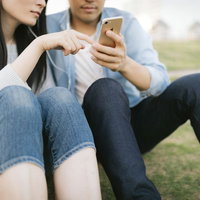 好きな曲をイヤホンで共有する恋人たちのスマートフォン音楽鑑賞の写真