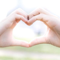 女性と男性の手でハートマークを作るラブラブ女子の写真