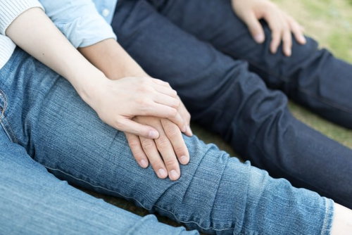 彼女のひざの上で手を重ねるカップルのラブラブなスキンシップシーン